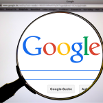 Google's logo under a magnifying glass - relates to  How Google Makes Money! Google's Staggering $80.5 billion Revenue i