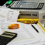 Income tax calculation on a cluttered desk -relates to Double Taxation Trouble? Capital Gains Tax & STT in Explained