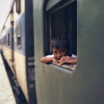 Boy sitting near train's Window seat - relates to How Indian Railways are Changing for a Profit Drive? What it Means